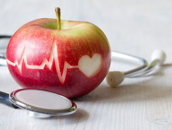 Heartbeat line on red apple and stethoscope, healthy heart diet concept background