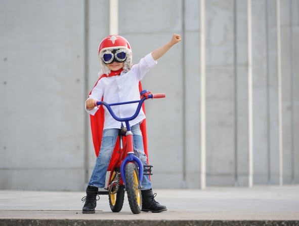 Kind Superman auf Fahrrad