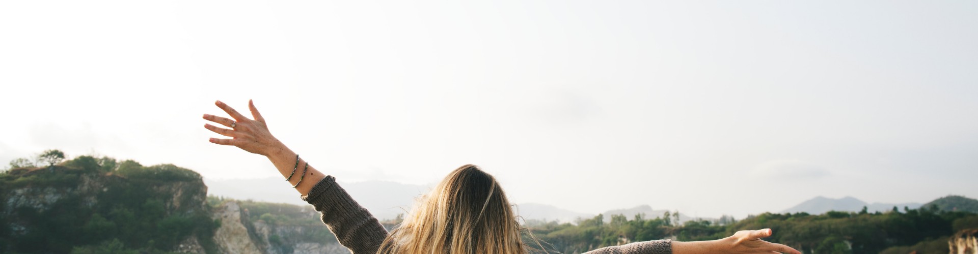 Frau mit geöffneten Armen vor Felsen