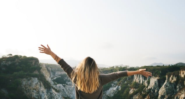 Frau mit geöffneten Armen vor Felsen