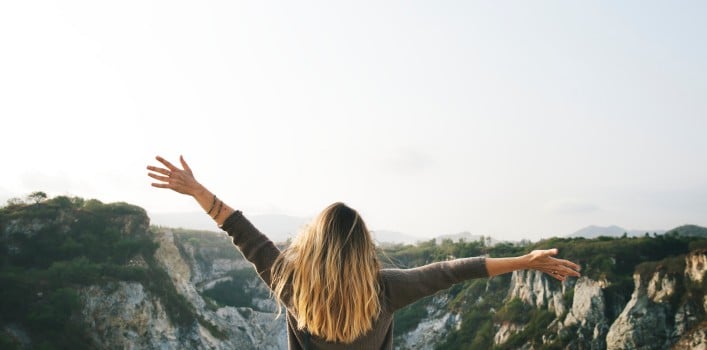 Frau mit geöffneten Armen vor Felsen